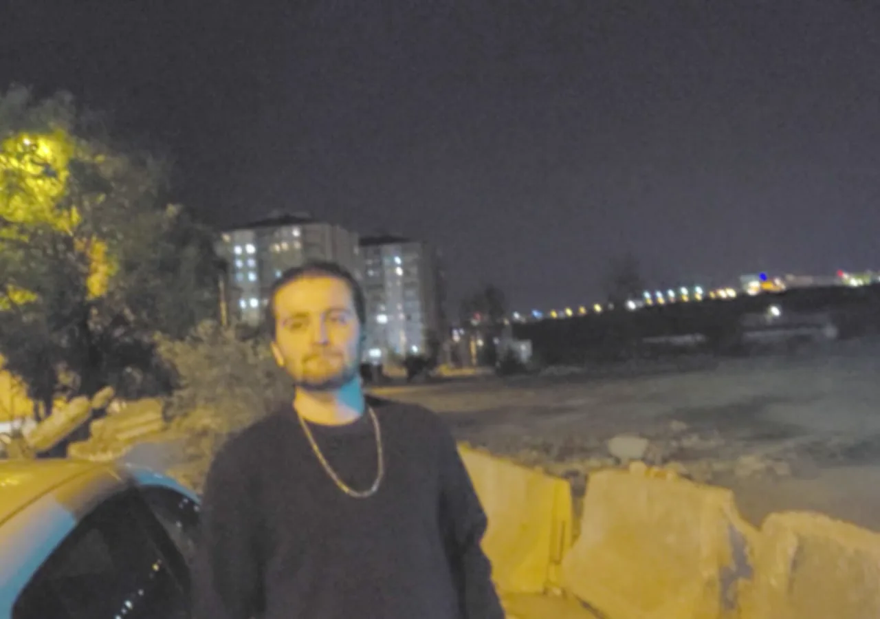 Sarı bariyerlerin yanında, gece şehir ışıkları